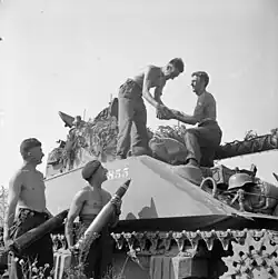 photographie en noir et blanc de soldats se passant des obus sur un char