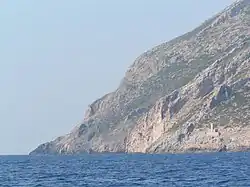 Pente rocheuse descendant quasi à pic sur la mer bleue ; ciel limpide