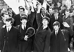 Photo de 4 jeunes hommes saluant la foule de la main.