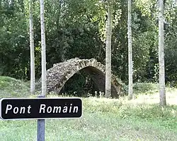 Vue d'un pont médiéval et de son panneau indicateur avec l'inscription fausse « pont romain »