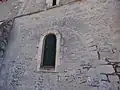 Des pierres sont disposées en arête-de-poisson au-dessus de l'arcade murée.