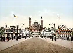 Photographie colorisée des pavillons de l'exposition de 1900 dans les jardins du Trocadéro avec, au loin, le palais.