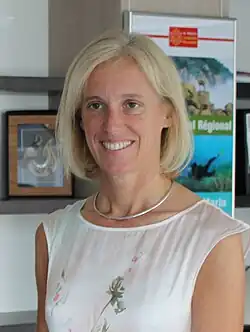 Photo d'une femme blonde souriante habillée en blanc.