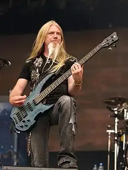 photo d'un homme blond avec une barbe jouant de la basse