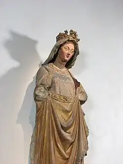 Photographie de la statue d'une femme sans bras, couronnée, et à la robe dorée.