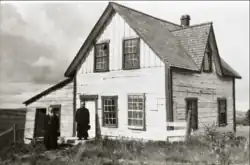 Deux hommes en soutane situés devant une maison.