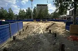 Zone en travaux avec des pieux métalliques dépassant du sol.