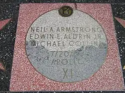Photographie en couleur d'un pavage commémoratif mentionnant les noms des astronautes d'Apollo 11.
