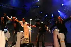 Cinq membres d'un groupe se tenant par la main à la fin d'un de leurs concerts