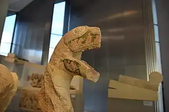 Tête monstrueuse, devant le serpent du coin gauche.
