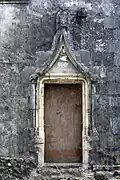 Porte de la maison du Sénéchal : un homme vêtu d'une robe courte et un autre vêtu d'une robe longue supportent la base des arcs, tandis qu'un ange couronne le frontispice