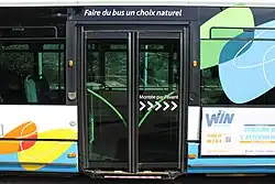 Photographie en couleurs des portes coulissantes fermées d'un autobus bleu et blanc.