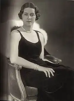 Photographie en noir et blanc d'une jeune femme assisse sur un fauteuil.