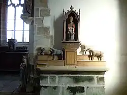 Retable, statue de Saint Eloi ferrant un cheval et ex-voto de chevaux en bois.
