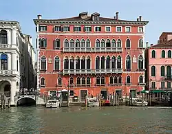 Au bord du canal où son amarrés trois bateaux, grand bâtiment couleur brique aux nombreuses fenêtres étroites disposées côte à côté.