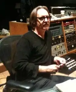 Photo de Butch Vig, le producteur de l'album, assis dans un fauteuil devant du matériel d'enregistrement.