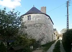 Photographie en couleurs d'une tour ronde surmontée d'une habitation avec une fenêtre.