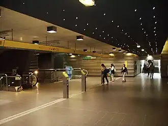 La salle des billets avec son plafond noir, les valideurs et les escaliers à gauche.