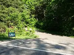 panneau portant l'inscription Pachyderm à l'entrée d'une route s'enfonçant dans la végétation.