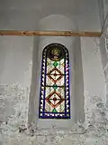 L'unique grand vitrail orné de décors végétaux et de fleurs : sur le médaillon est représentée la Vierge Marie avec l'Évangile.