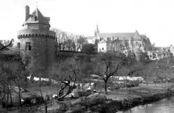 Photographie en noir et blanc de la tour du Connétable dans son environnement, le verger des douves, les remparts vers le nord, la cathédrale en arrière-plan. Photo prise vers 1900