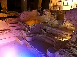 Photographie en couleurs de vestiges de constructions romaines sous lumière artificielle.