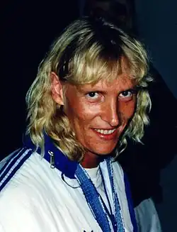 Mette Bergmann trägt eine weiße Trainingsjacke mit blauen Streifen auf der Schulter.