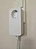 dLAN650, älterer PowerLAN-Adapter von Devolo mit Steckdosen-Durchschleifung sowie angeschlossenem LAN-Kabel[12]