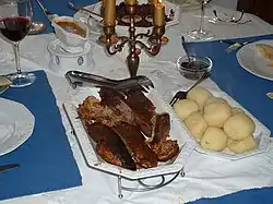 Auf einem gedeckten Tisch stehen jeweils eine Schale mit Rotkohl, Klößen und Teilen eines Gänsebratens
