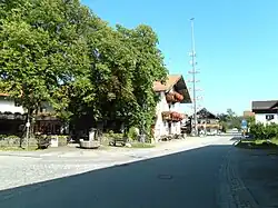 Dorfstraße in Grainbach mit der Traditionsgaststätte Maurer (links im Bild); vor deren Biergarten der Samerbrunnen, flankiert von zwei Sitzbänken