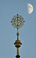 Die Turmspitze bildet ein Marienmonogramm als Wetterfahne