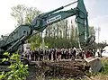 Der vom Innenminister Joachim Herrmann bediente Kettenbagger Liebherr R 944 mit Verstellausleger, im Hintergrund Zuschauer und protestierende Umweltaktivisten