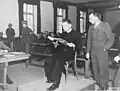 Der polnische Priester Theodore Korcz (links) liest am 22.&nbsp;November 1945 im Beisein von Hauptankläger Denson aus den Malariaprotokollen vor