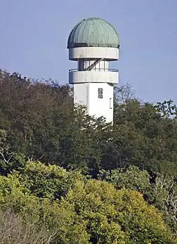 Ein weißer Turm mit einer türkisen Kuppel inmitten von Wald