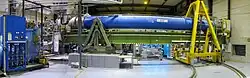 Das CAST-Experiment am europäischen Kernforschungszentrum CERN. Dargestellt ist der supraleitende CAST-LHC-Magnet mit Nachführsystem und das Helium-Kühlsystem zum Betrieb des Magneten (links).